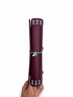 Burgundy full size journal shown from the side with powder-blue elastic band, silver eyelets, and blue mushroom band charm