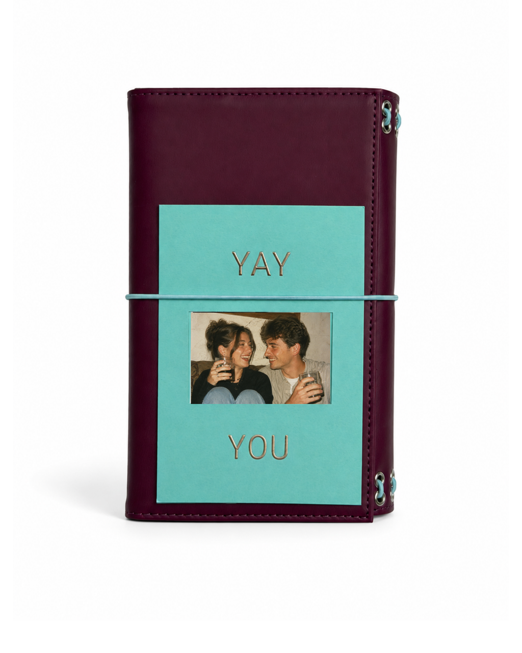 Burgundy full size journal styled with the double-sided gold-foil “Yay You” photo keepsake card beneath the powder-blue elastic band.