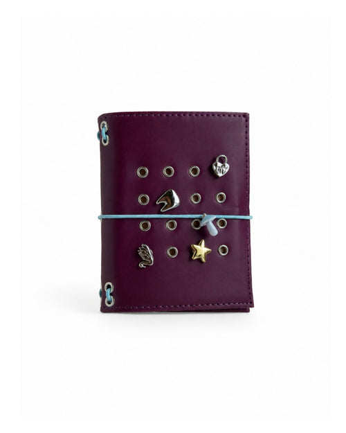 Burgundy Pocket Journal with a powder-blue elastic band and four removable KEPT cover charms on a white background.
