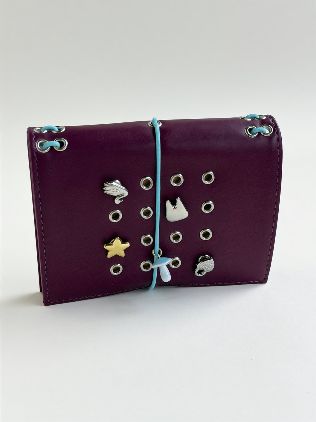 Burgundy pocket journal standing horizontally with its elastic band and KEPT charms styled on the cover