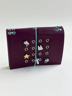Burgundy pocket journal standing horizontally with its elastic band and KEPT charms styled on the cover