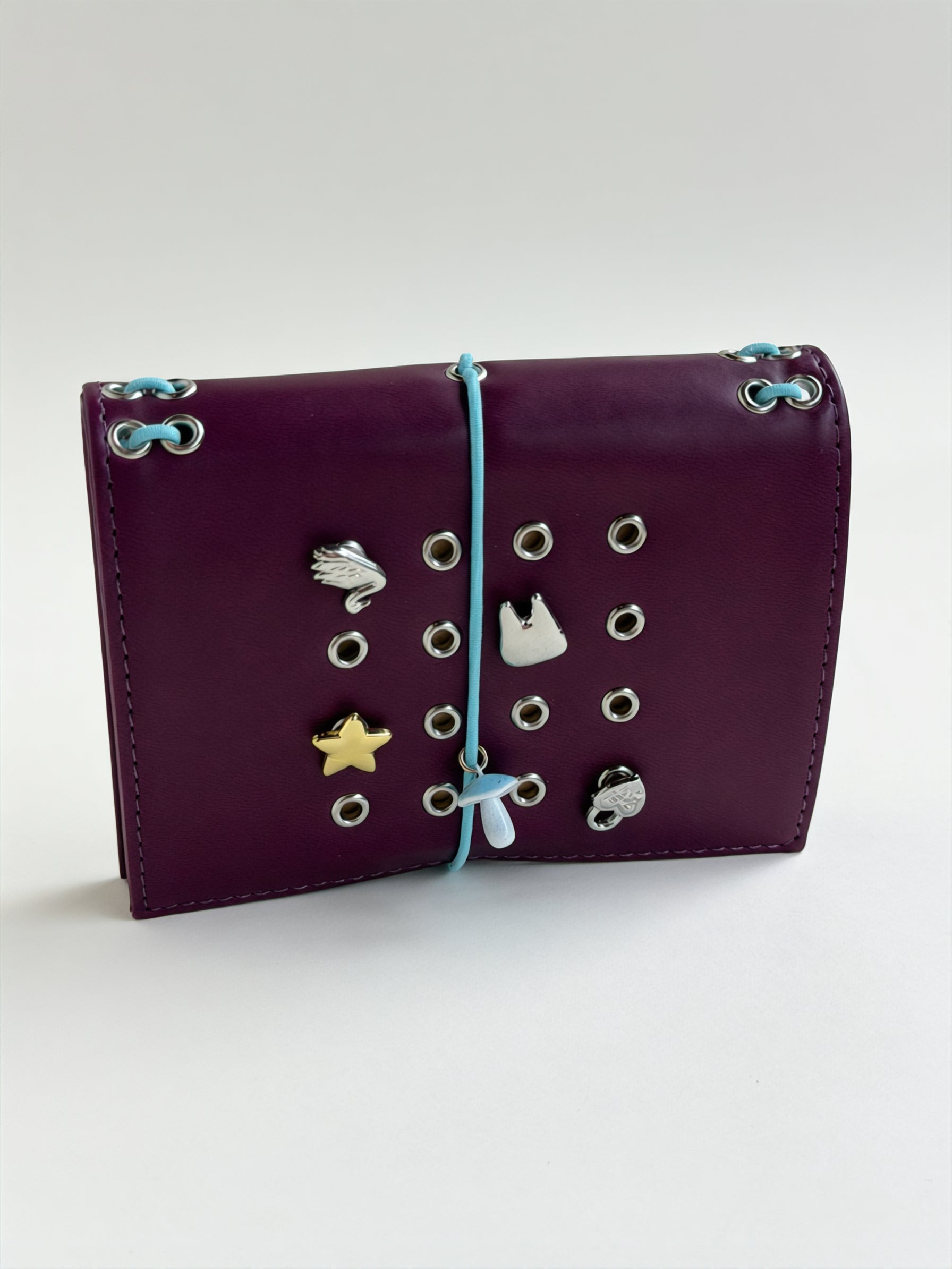 Burgundy pocket journal standing horizontally with its elastic band and KEPT charms styled on the cover