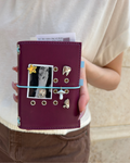 A Burgundy Pocket Journal styled with a powder-blue elastic band, removable KEPT charms, and a black-and-white photo insert.