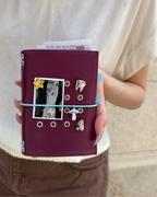 A Burgundy Pocket Journal styled with a powder-blue elastic band, removable KEPT charms, and a black-and-white photo insert.