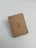 Back view of the Camel Radish Pocket Journal with a textured camel-colored PU cover and blush-pink elastic band.