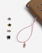 Detail view of the Camel Radish Full Size Journal beside its blush-pink elastic band, pink radish charm, and four removable KEPT cover charms on a white background.