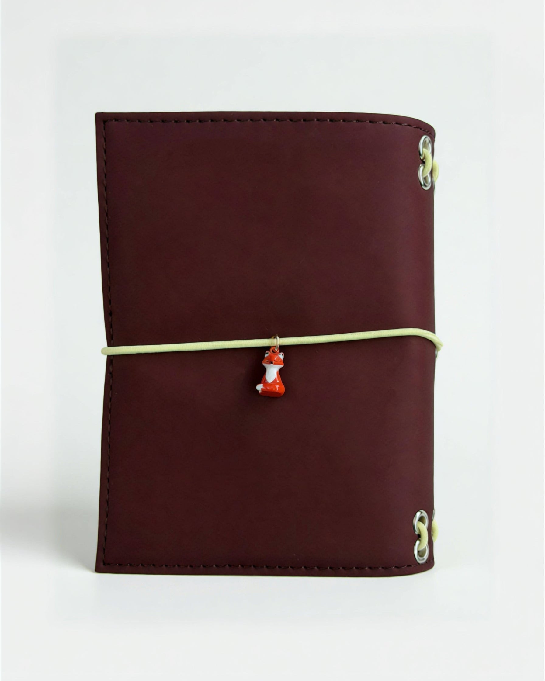 Back view of the Chestnut Fox pocket journal with a butter-yellow elastic band and fox charm