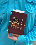 A person holds an Chestnut Fox Pocket Journal styled with a butter-yellow elastic band, fox charm, four removable KEPT cover charms, and a photo insert.