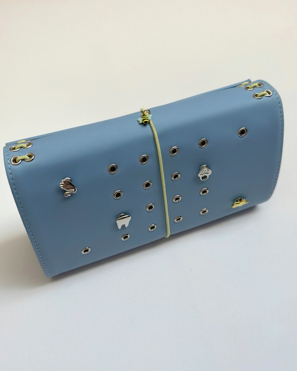 Mist Blue full size journal displayed horizontally with a butter-yellow elastic band, bee charm, and removable KEPT cover charms.