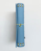 Spine view of the Mist Blue full size journal showing yellow lacing, metal eyelets, butter-yellow elastic band, and a bee charm.