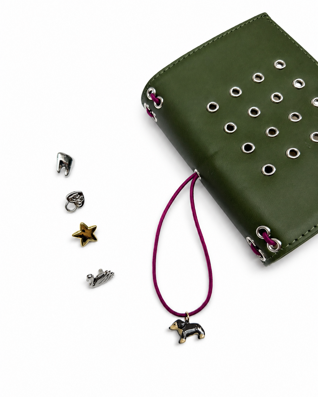 Olive pocket journal shown with its burgundy elastic band, dachshund charm, and removable KEPT cover charms displayed beside it

