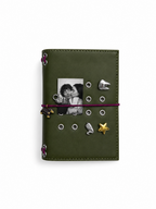 Olive pocket journal displayed upright with a personal photo, burgundy elastic band, dachshund charm, and removable cover charms