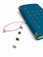 Teal Full Size Journal with a textured PU cover and metal eyelets, displayed beside its blush-pink elastic band and four removable KEPT cover charms.