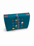 Teal pocket journal displayed horizontally with a blush-pink elastic closure, scissors charm, and KEPT cover charms